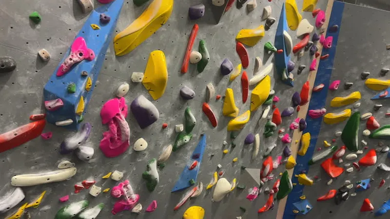 A climber topping out on a tall indoor boulder